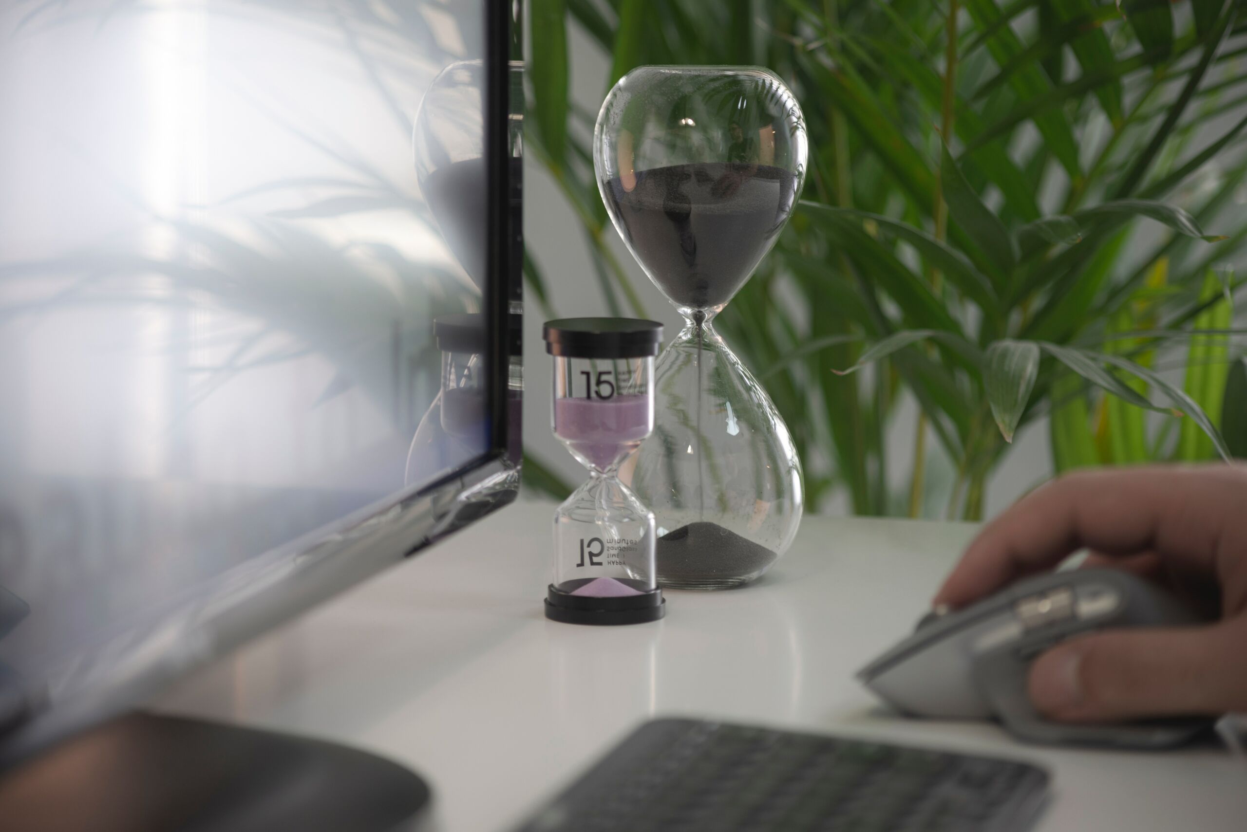 Two Hour glasses next to a computer monitor