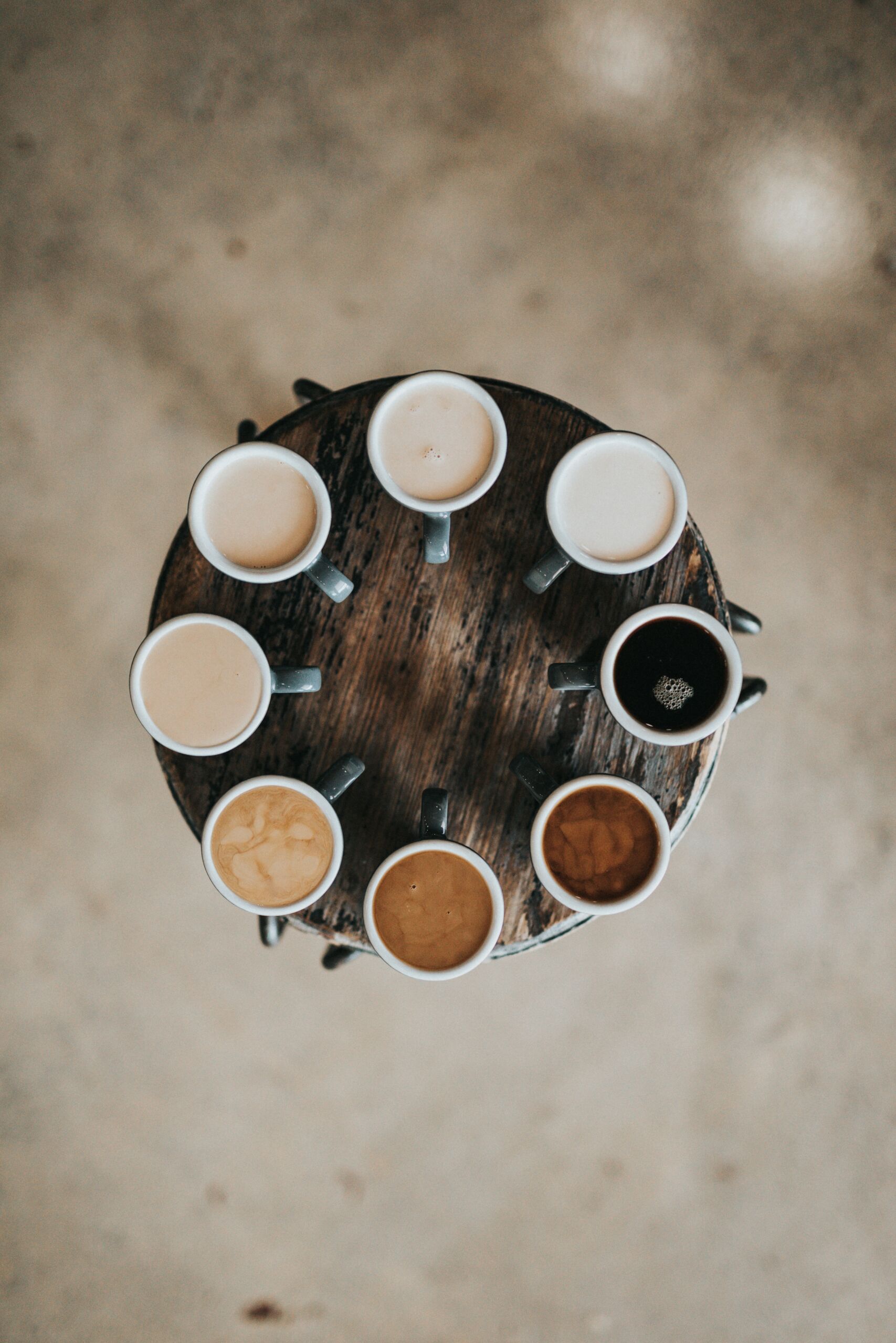 8 coffee cups with different amounts of cream in them.