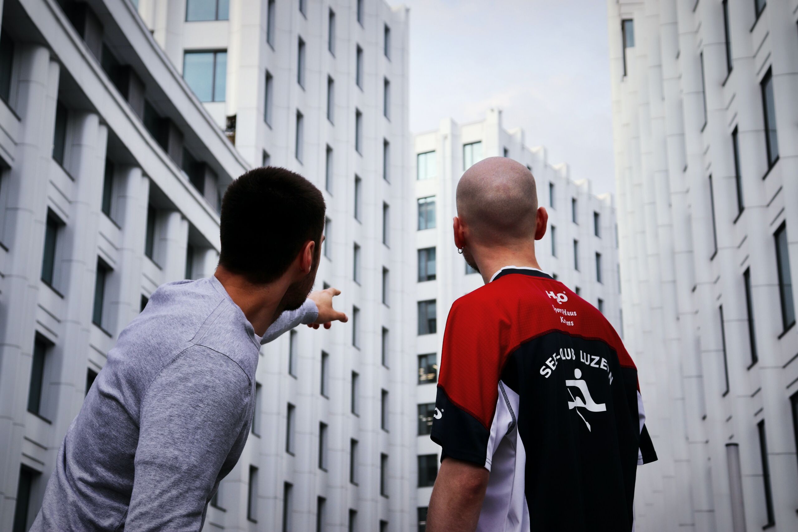 two people in a city and one of them is pointing to a building.