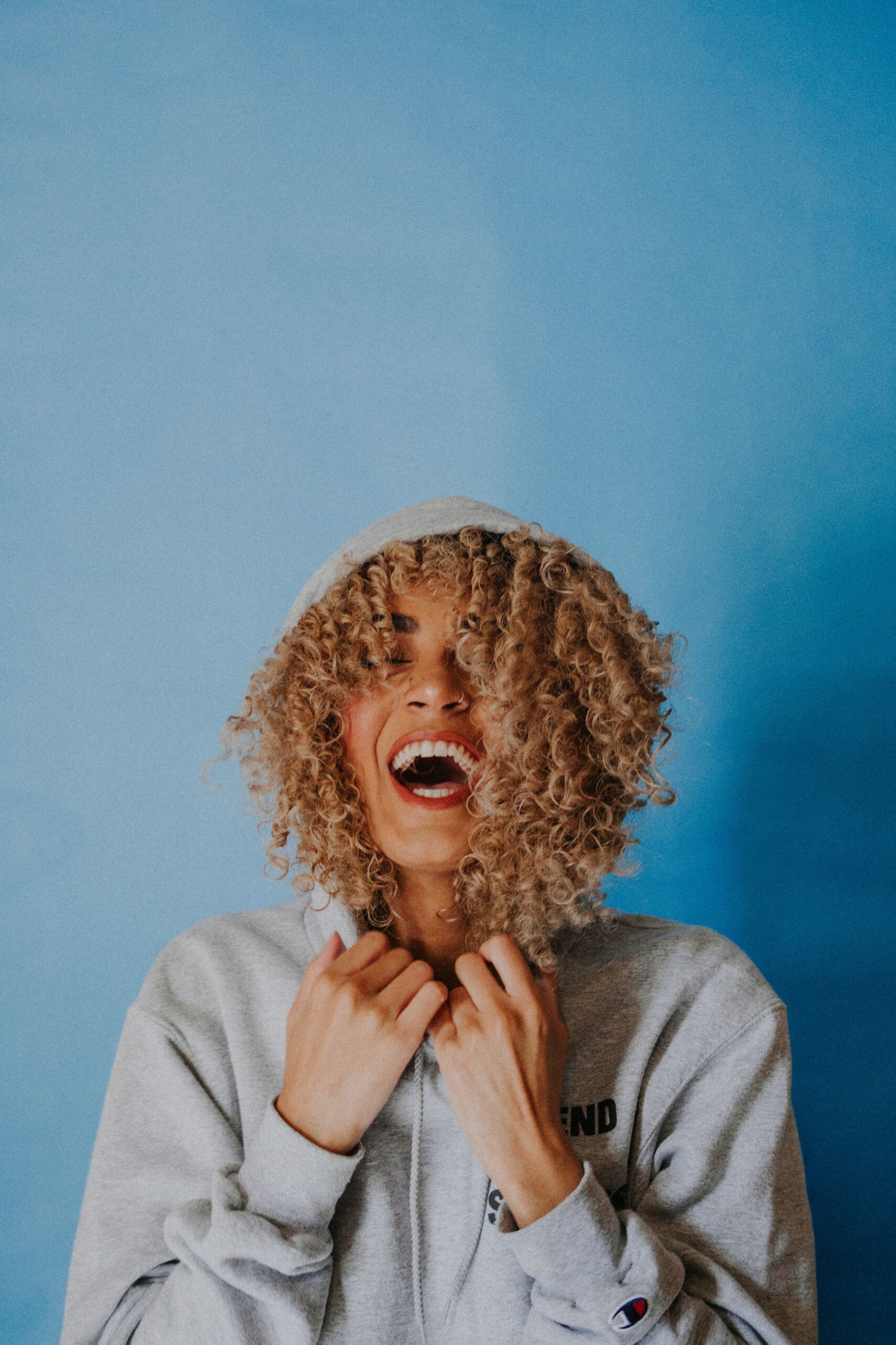 Woman laughing wearing a hoodie